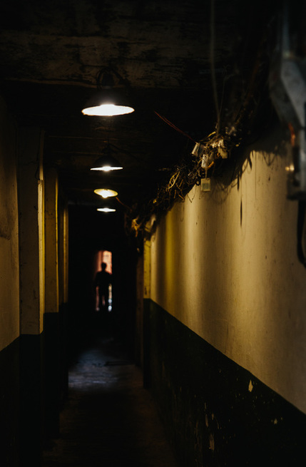 Shadowy man walks through a dark and narrow passageway into the hidden parts of Hanoi, Vietnam