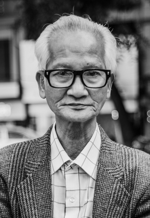 White haired Vietnamese man with glasses poses for a portrait