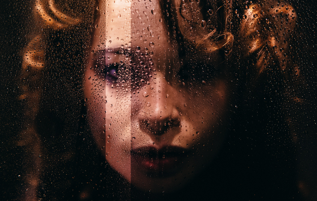 close-up portrait of American girl behind wet glass