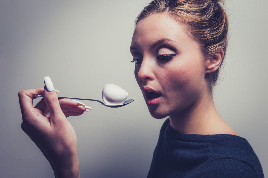 model holding a spoon with an egg
