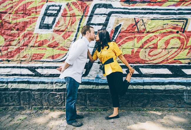 couple kissing in front of graffiti