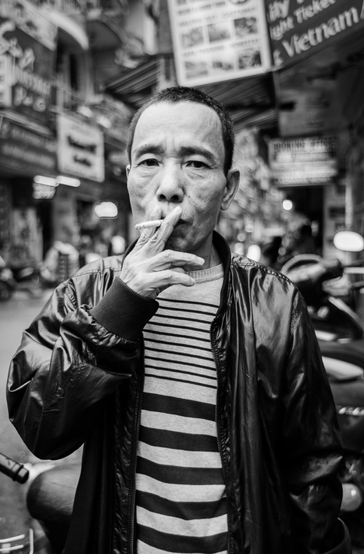 tough old Vietnamese man smokes a cigarette in his leather jacket