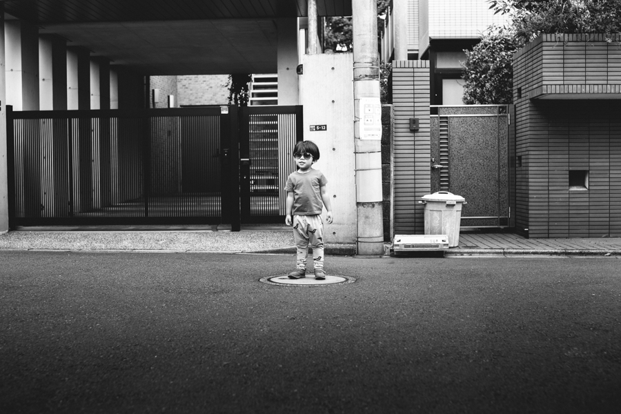 boy standing in street black and white