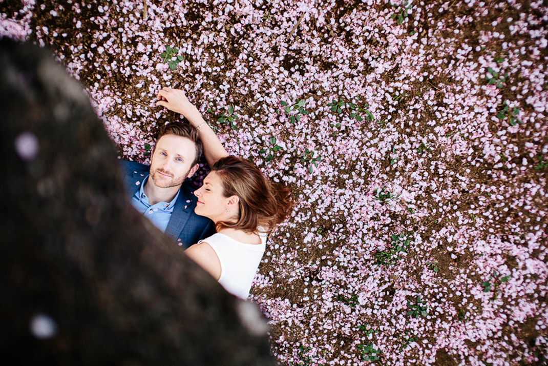 man and woman lay in cherry blossoms