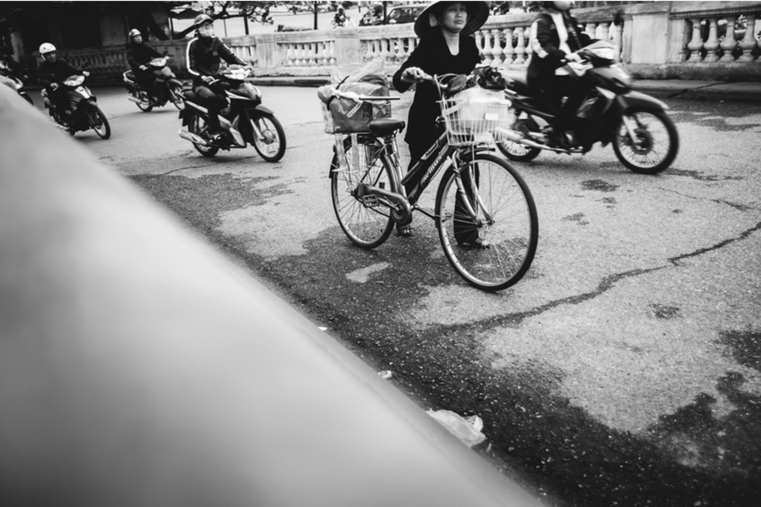 lady pushing bike in Hanoi